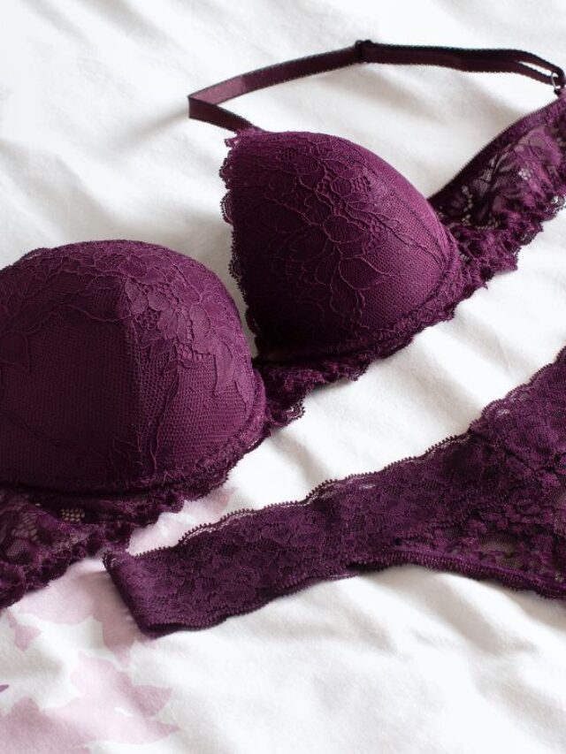 lingerie roxa em cima de uma cama com lençol branco