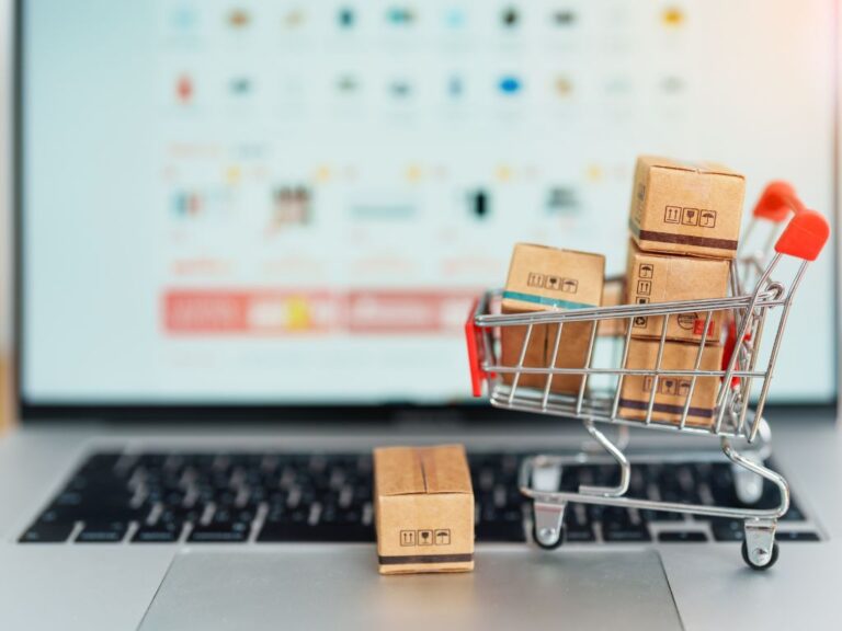 computador e mini carrinho de compras para ilustrar um post sobre como vender no mercado livre