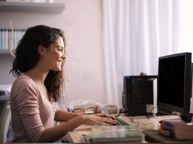 mulher usando computador e sorrindo