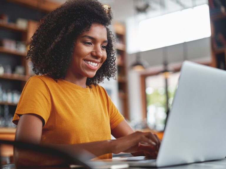 mulher sorridente usando computado para emissão de comprovante CNPJ