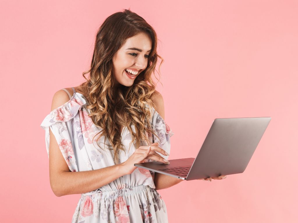 mulher sorrindo com computador na mão aprendendo a montar sex shop online