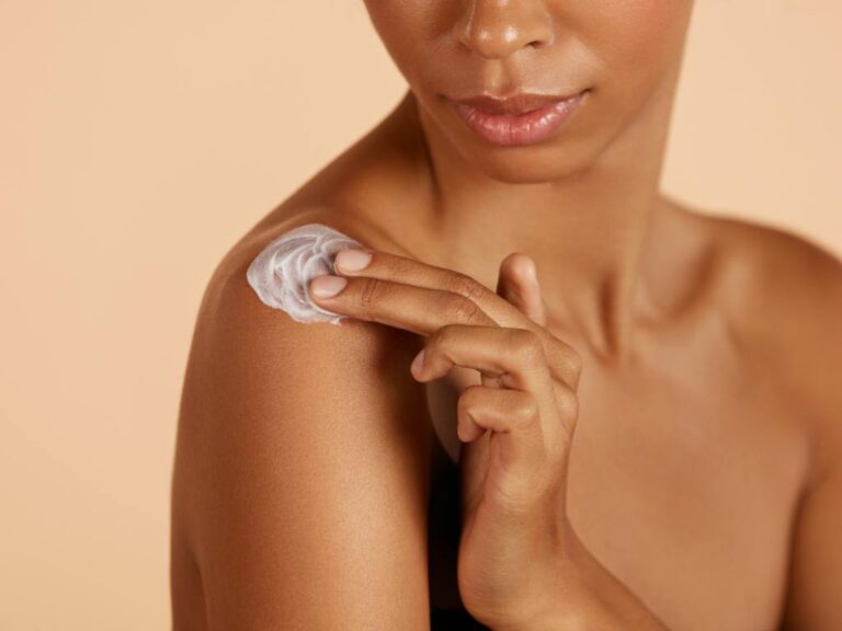Mulher passando creme hidrante no ombro