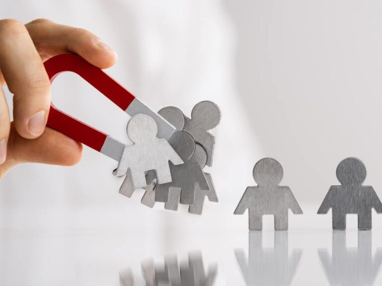 Representação de conquistar clientes, na imagem há uma mão usando um ímã puxando pessoas