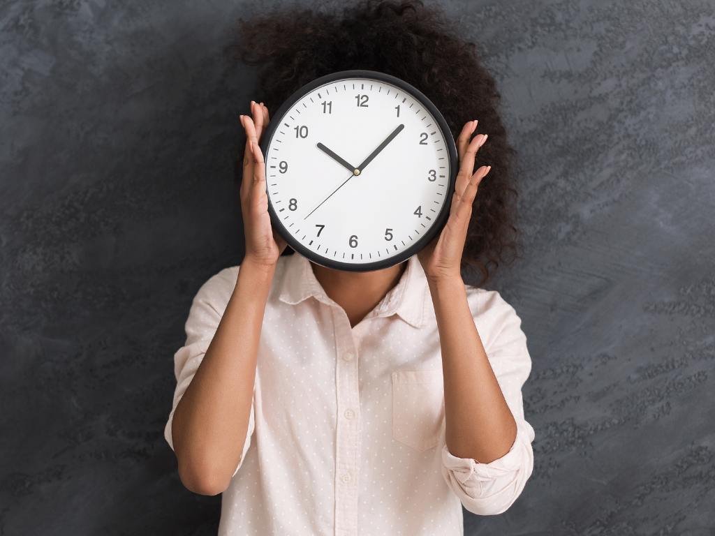 Mulher segurando um relógio na frente de seu rosto