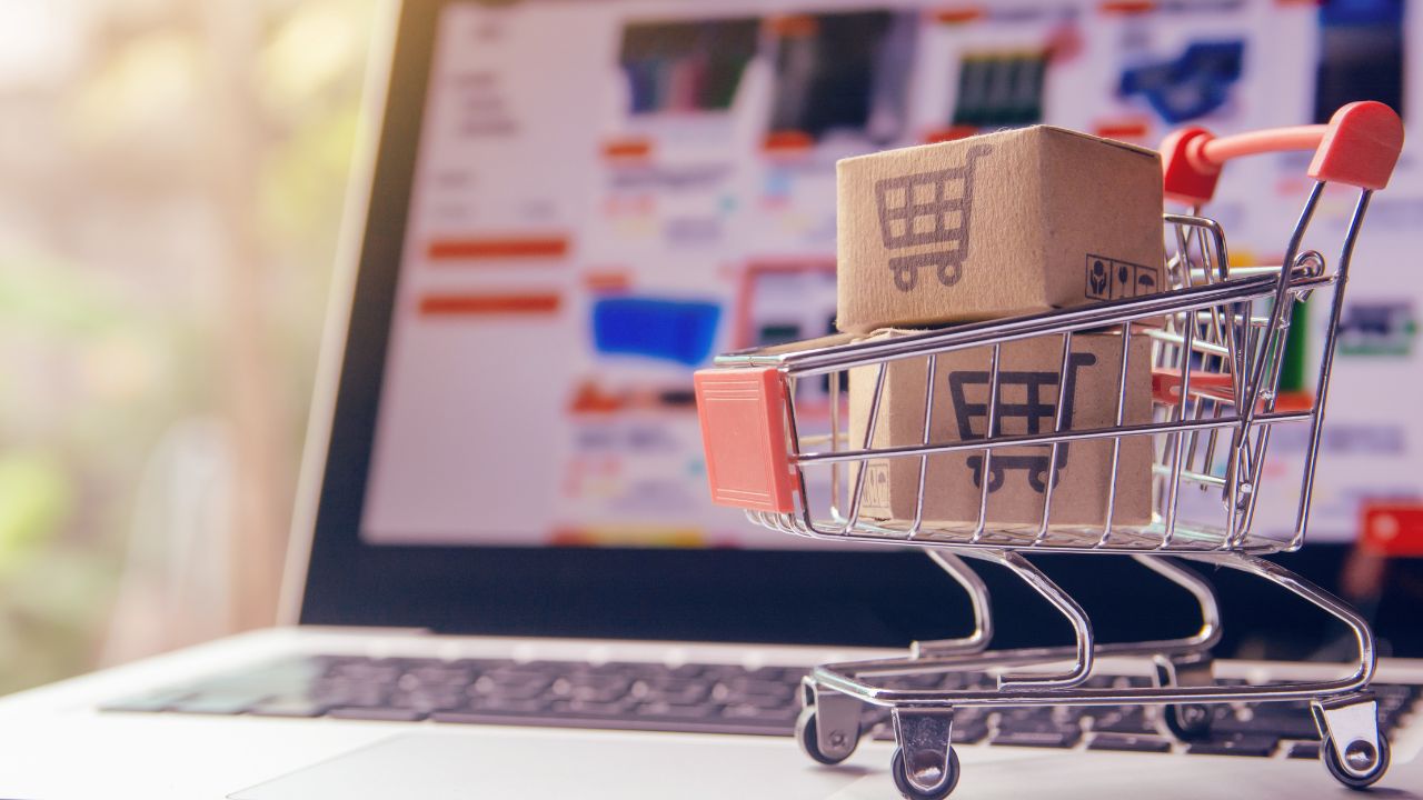 computador logado na temu e um carrinho pequeno de compras na frente